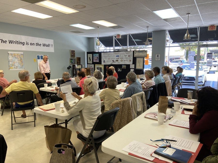 Room full of people sitting at tables in an Adult Writers Workshop at Laura Riding Jackson office